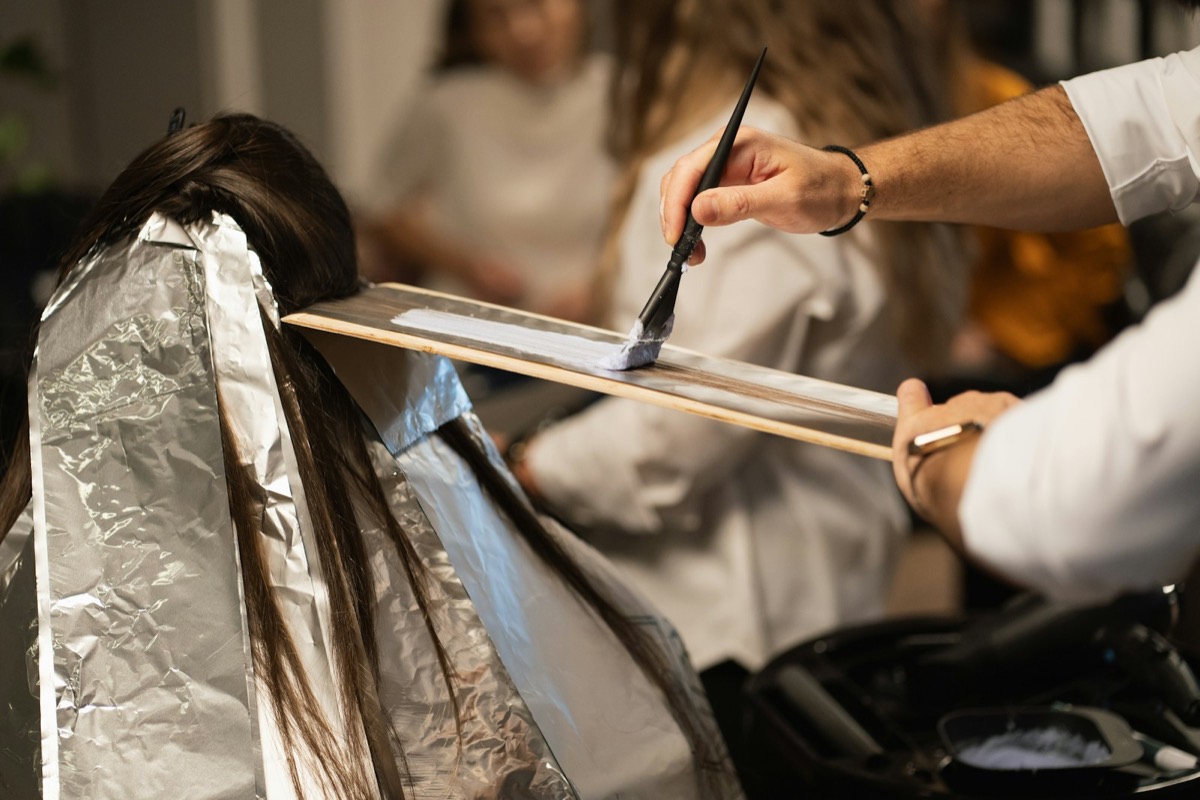 A colourist applying foils to a client in a salon