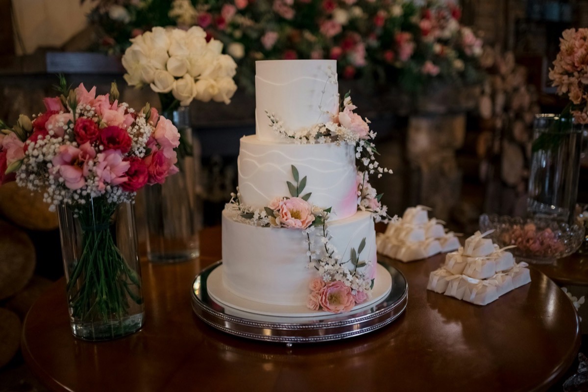 A three-tier white wedding cake decorated with pink flowers